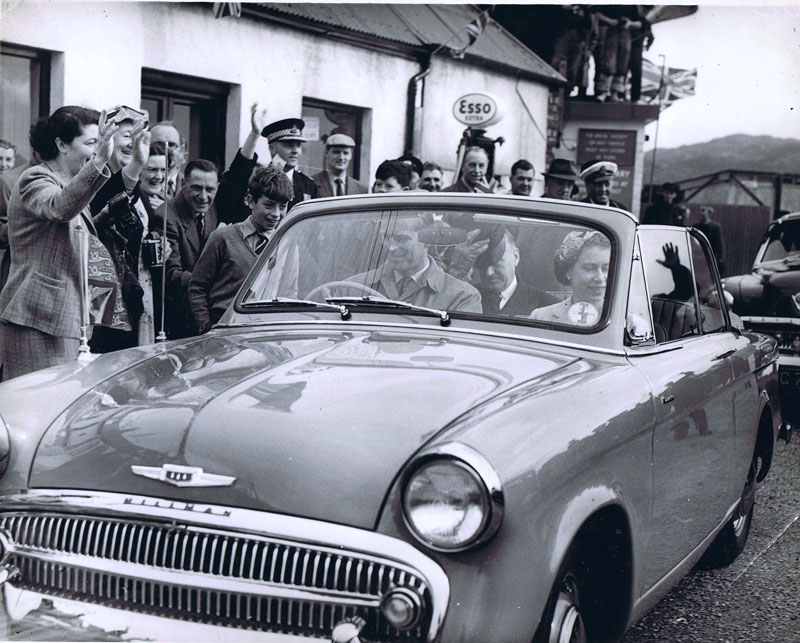 1956 - Royal Visit to Kyleakin:
Left to right:  Agnes Soper (waving), Mary MacLeod (left of car aerial), Marcus Soper (right of car aerial), right of petrol pump - Murdo John Nicolson, Roy Ham (with the white Cap), Prince Philip driving with Queen Elizabeth beside him.
If anyone else knows the names of anyone else in this picture, please let us know.
