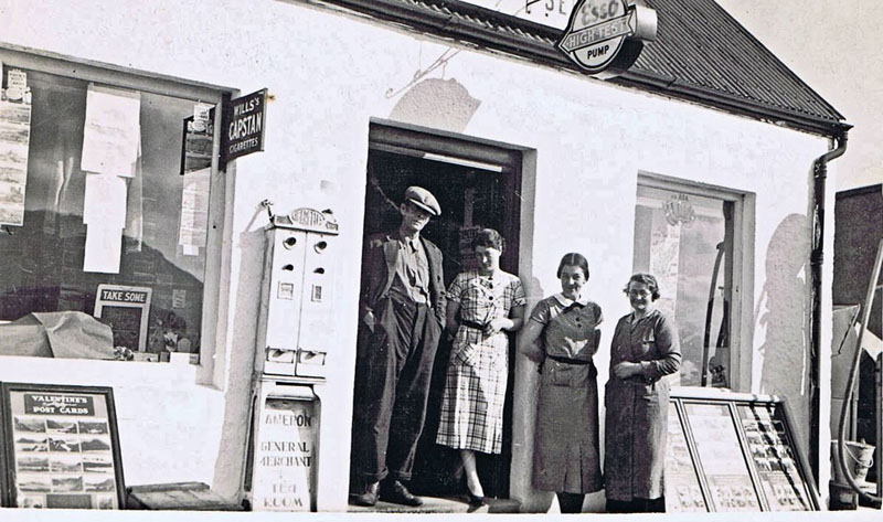 1937/38 - Outside Cameron's Stores, Kyleakin:
Left to right: Charlie Cameron, Agnes Cameron, Catriona  Finlayson (Tats) and Jane Cameron.
Note the cigarette machine and racks of postcards outside the shop